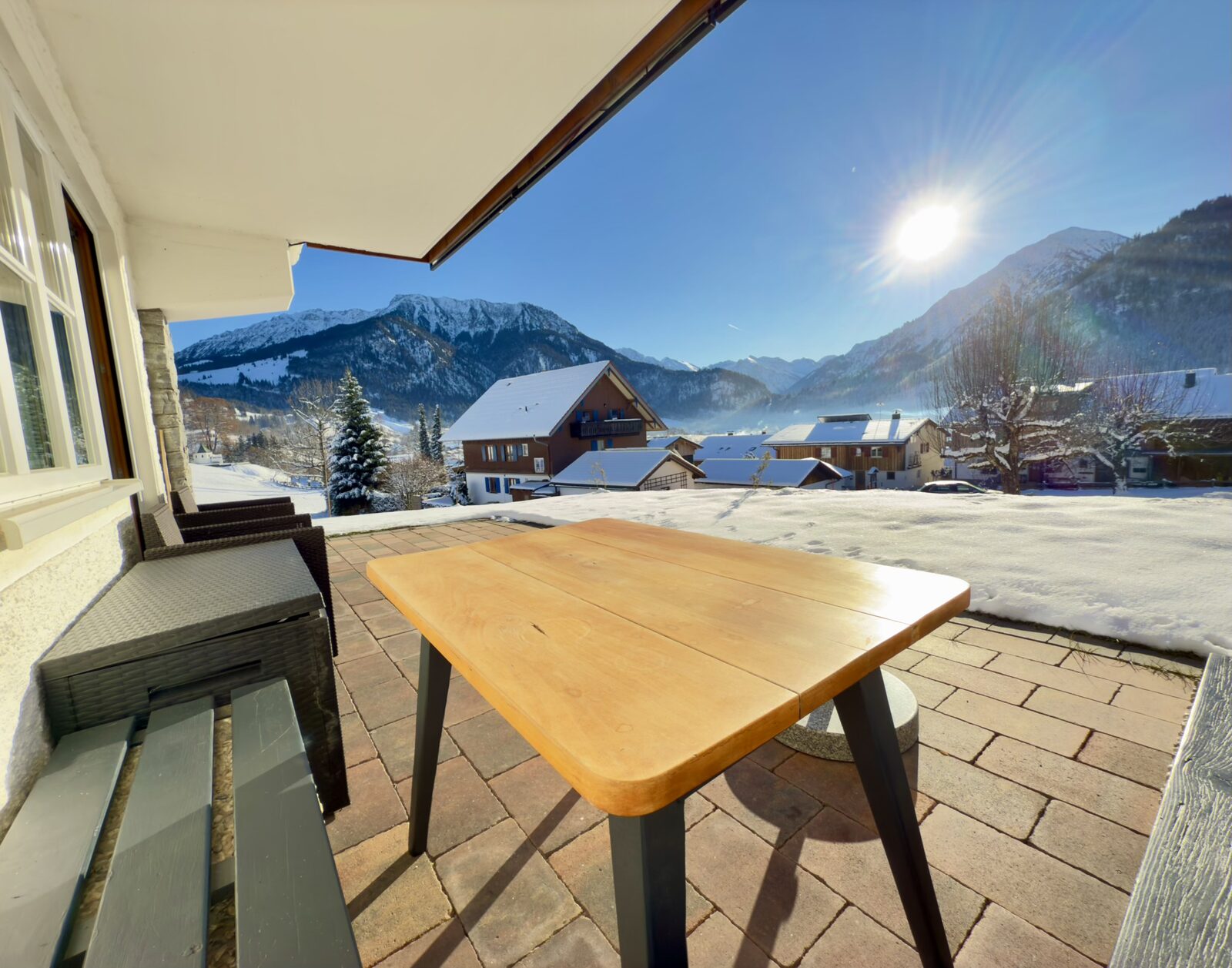 Terrasse mit Tisch und Blick auf die verschneiten Berge
