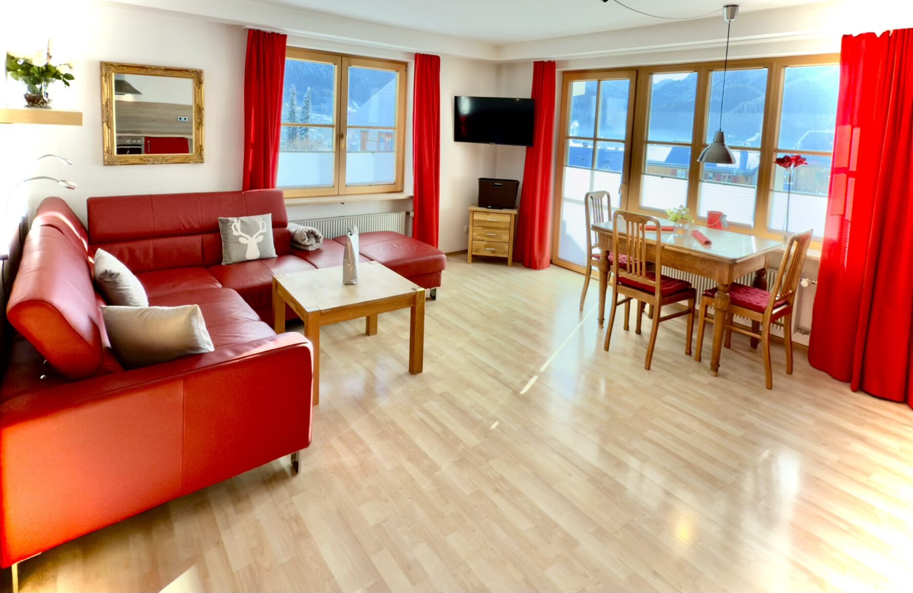 Wohnzimmer der Ferienwohnung mit roter Couch und Blick auf die Berge